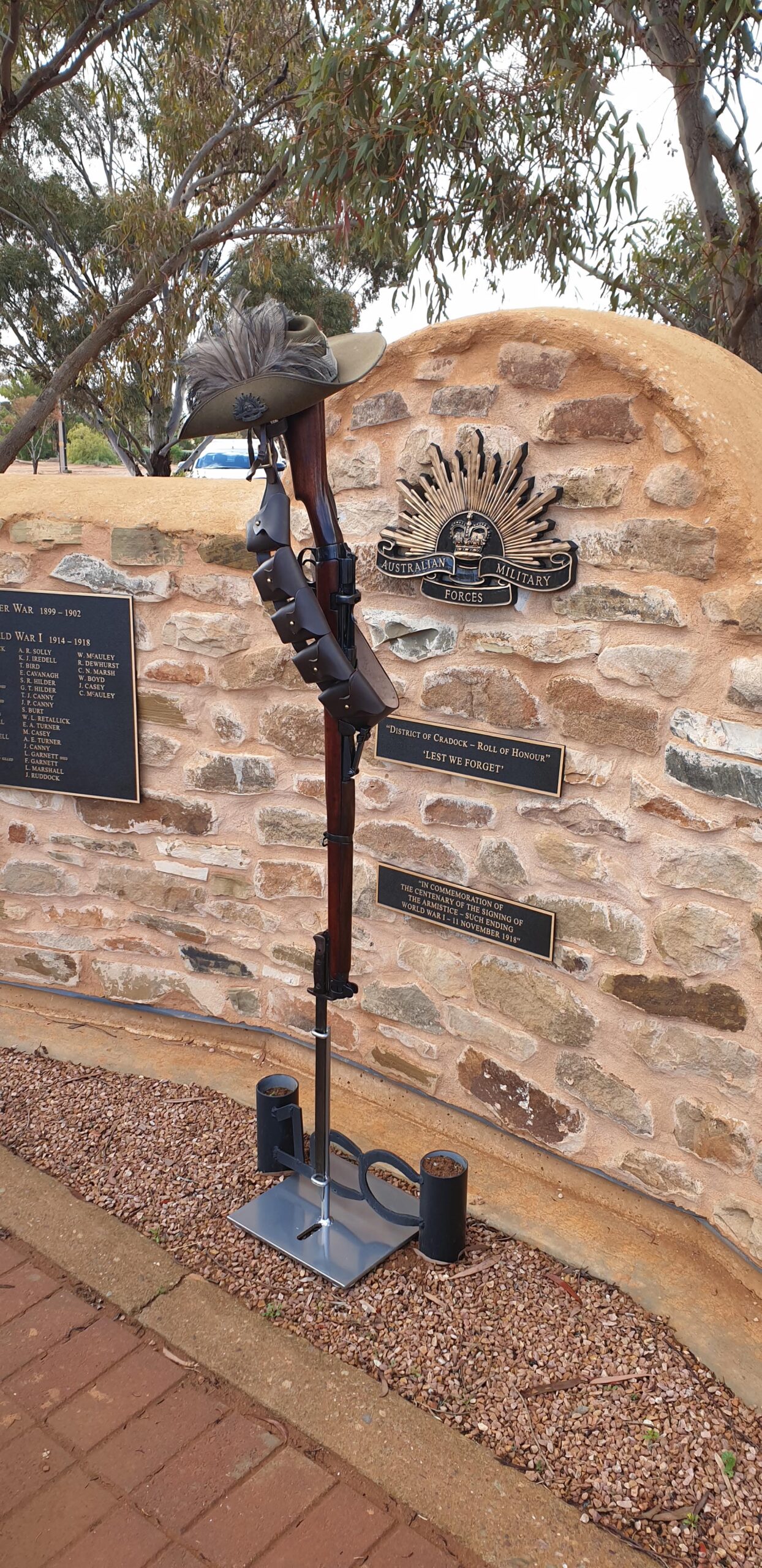 A stone memorial commemorating the end of WW1 with rifle, slouch hat and ammo belt